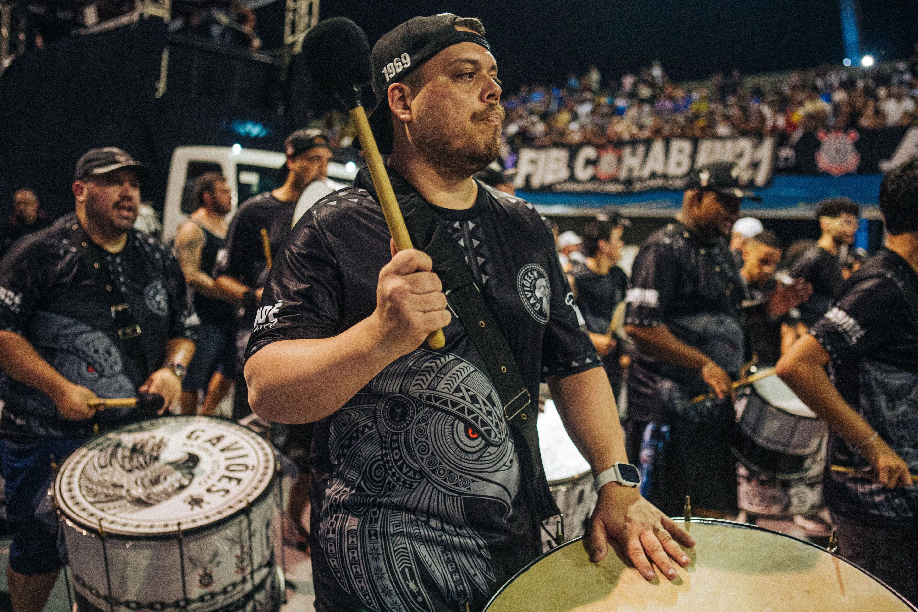 Samba-school percussionists playing large drums at a night gathering