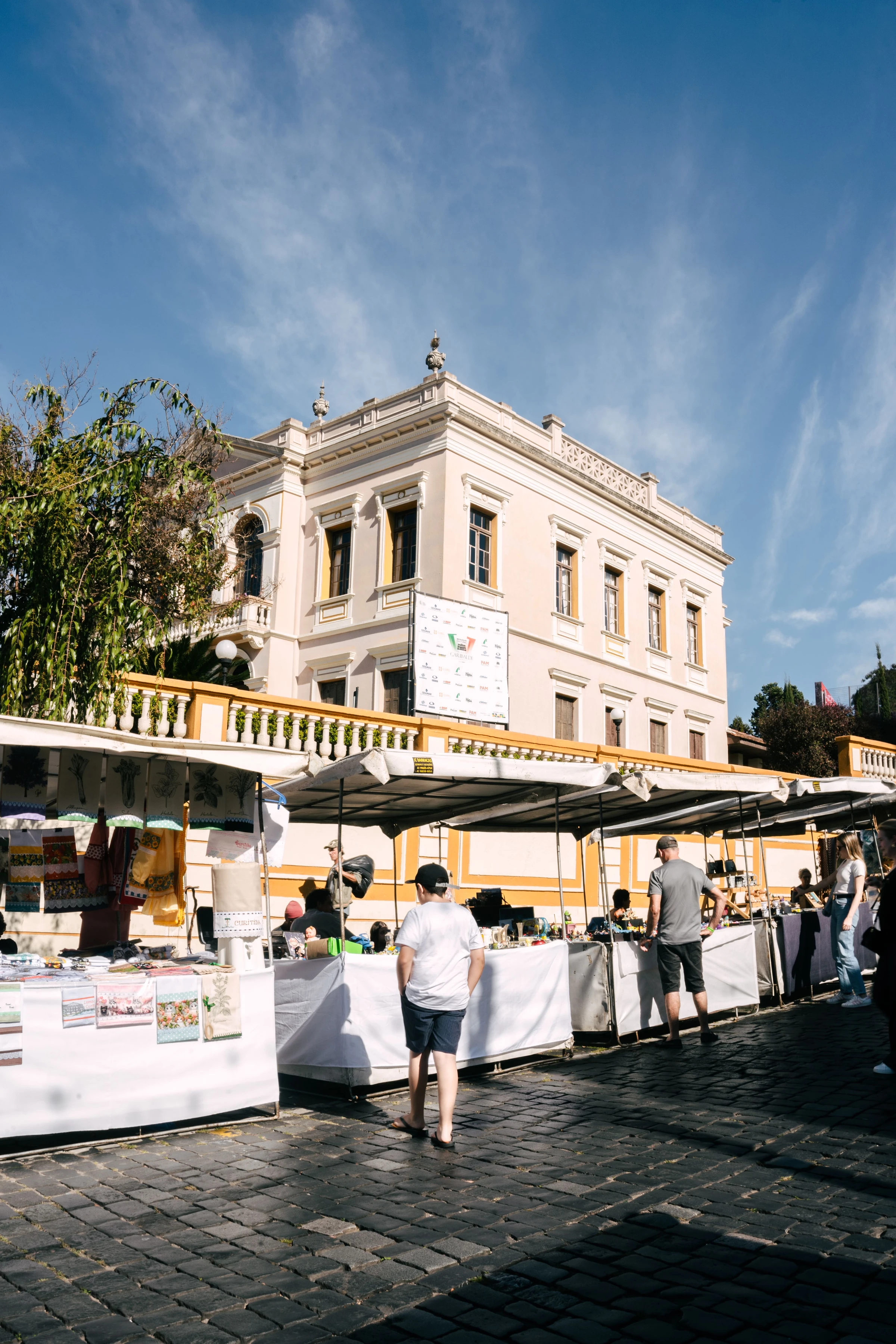 Historic architecture and market activity beneath a blue sky in central Curitiba.