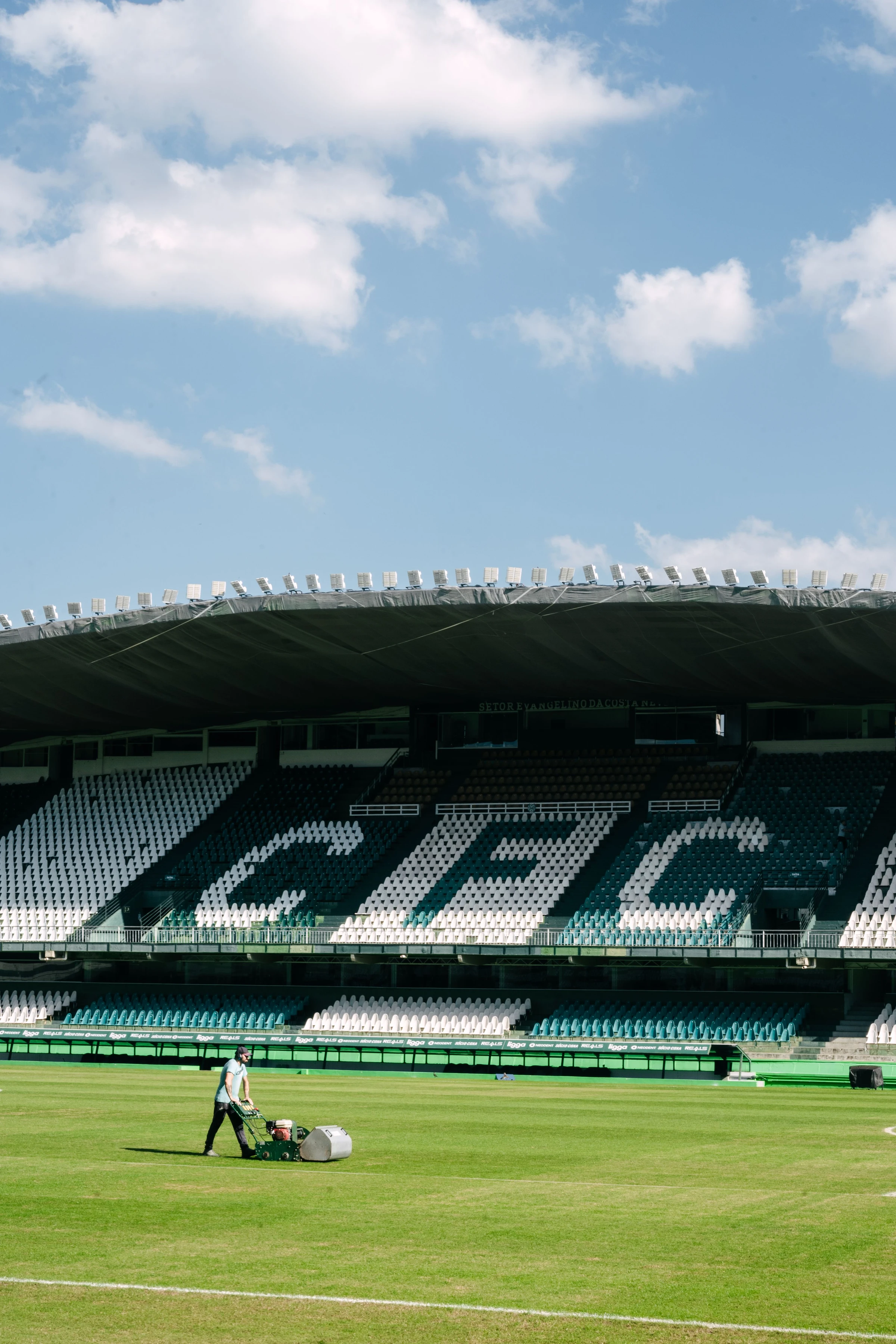 A maintenance worker stands beneath the green-and-white seating at Couto Pereira stadium in Curitiba.