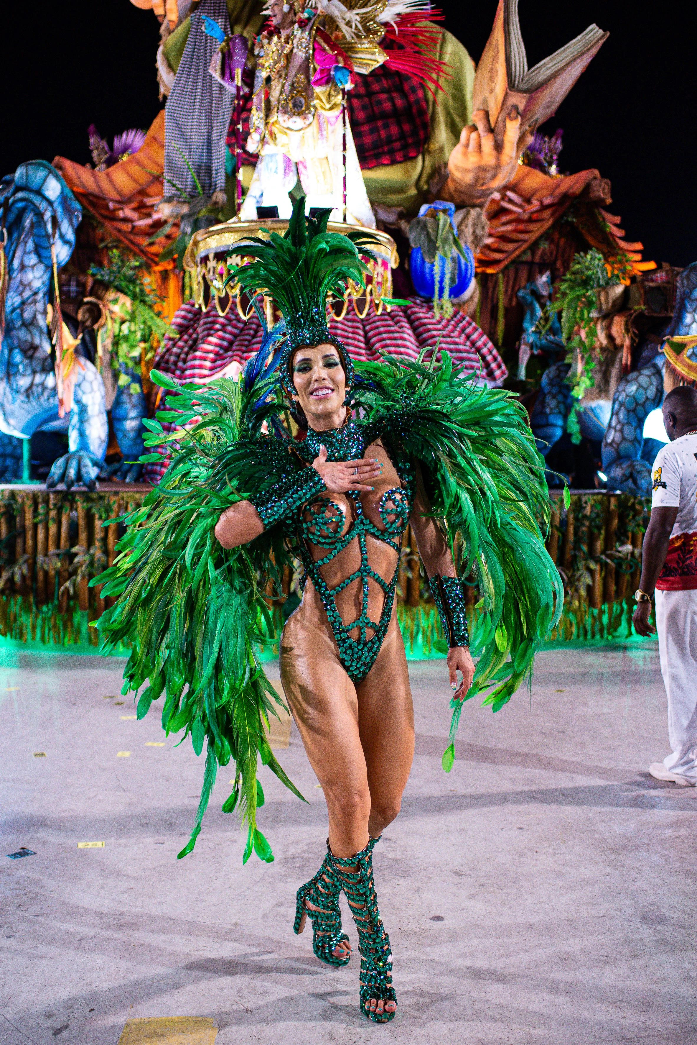 A dancer in green feathered Carnival costume performs at a Brazilian parade