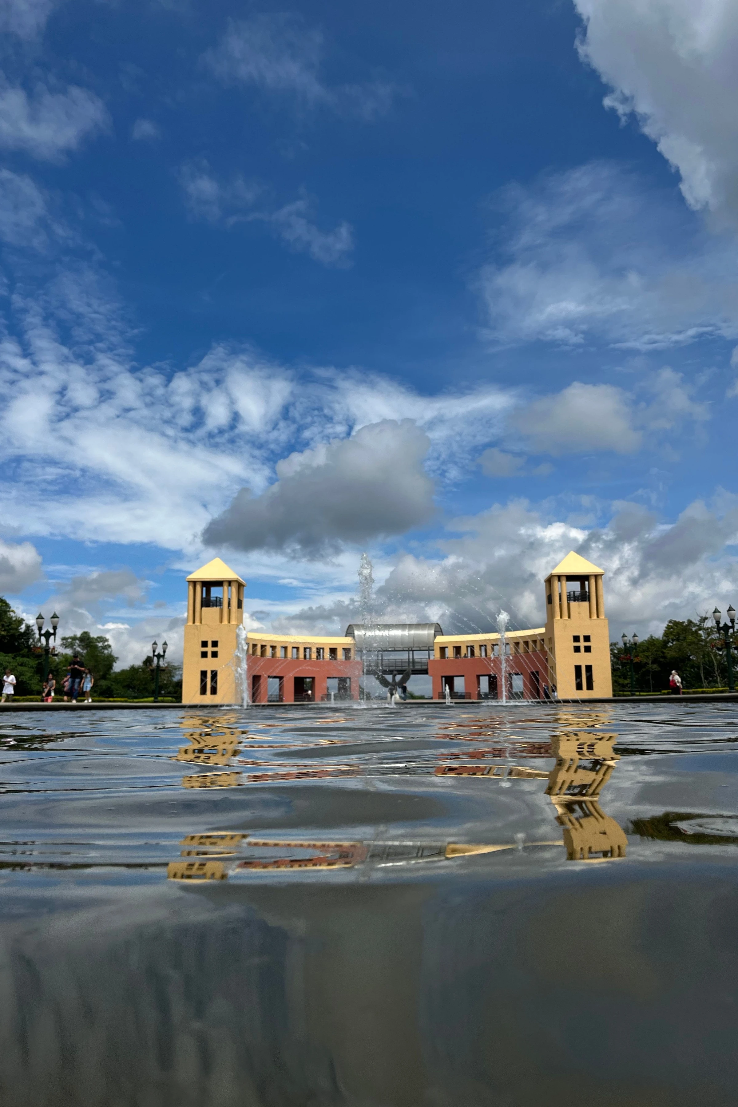 The towers of Parque Tanguá rise above reflective water beneath a vivid blue Curitiba sky.