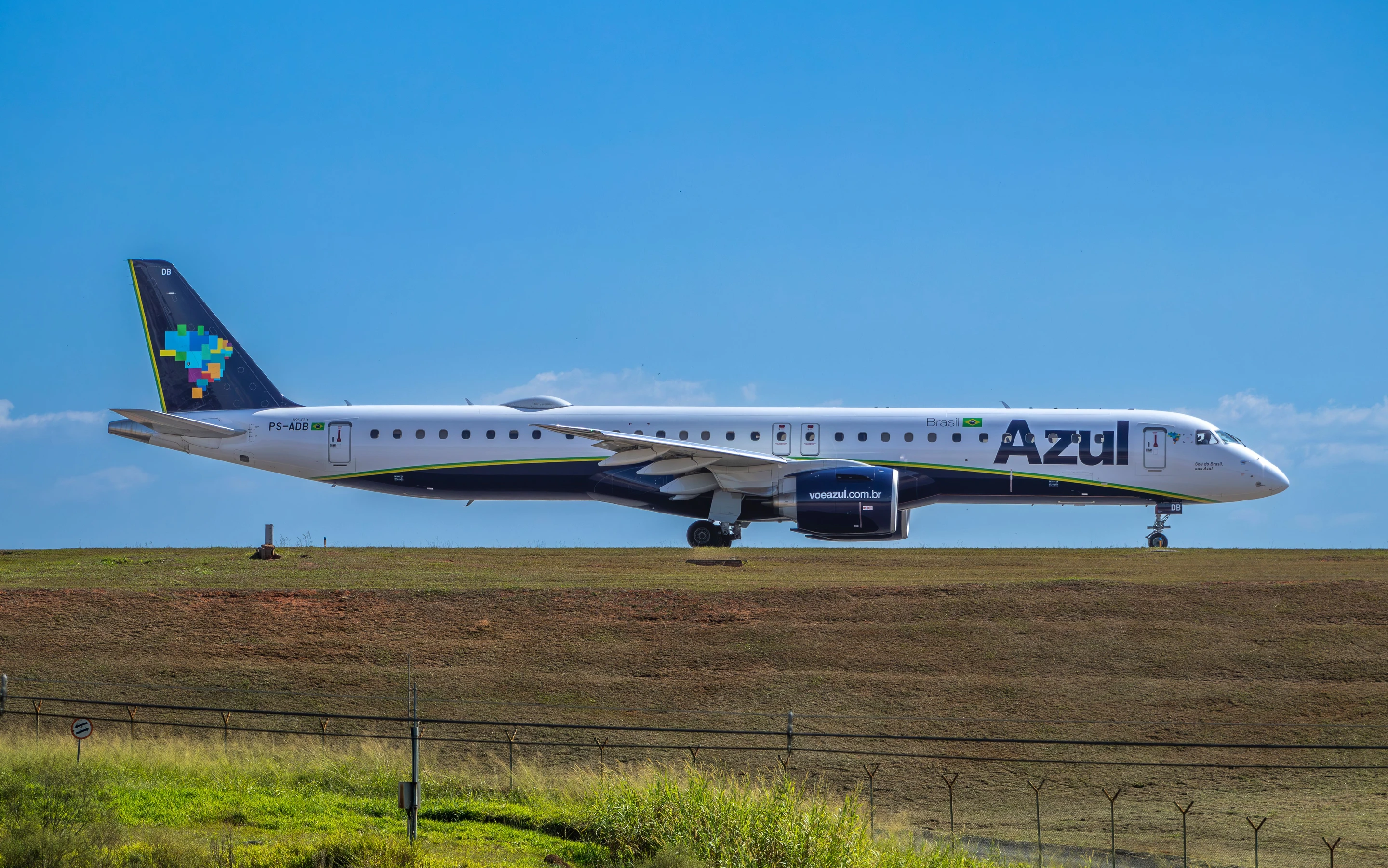 A blue and white Azul passenger jet stands beneath a clear Brazilian sky.