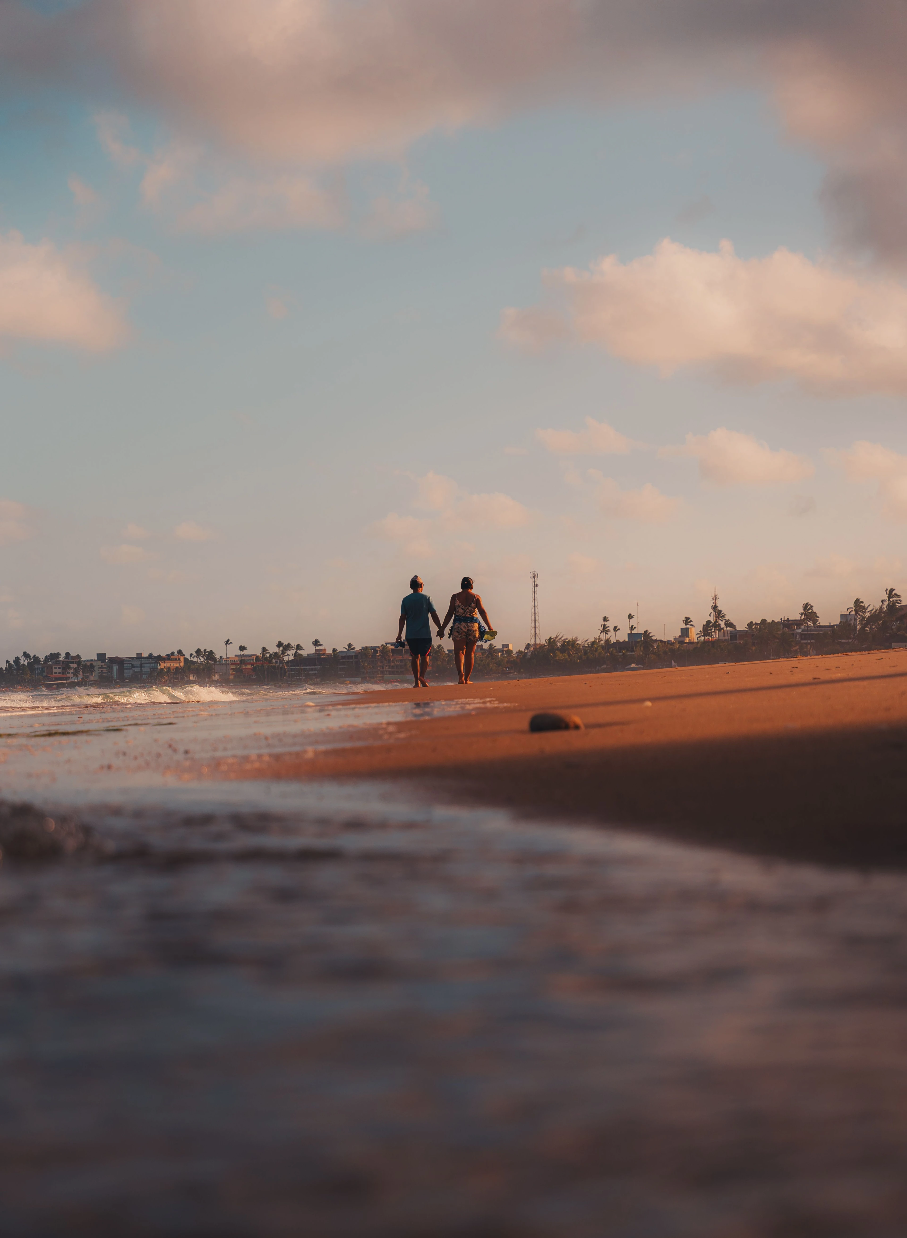 Two people walk together along the Porto de Galinhas shore in warm low light