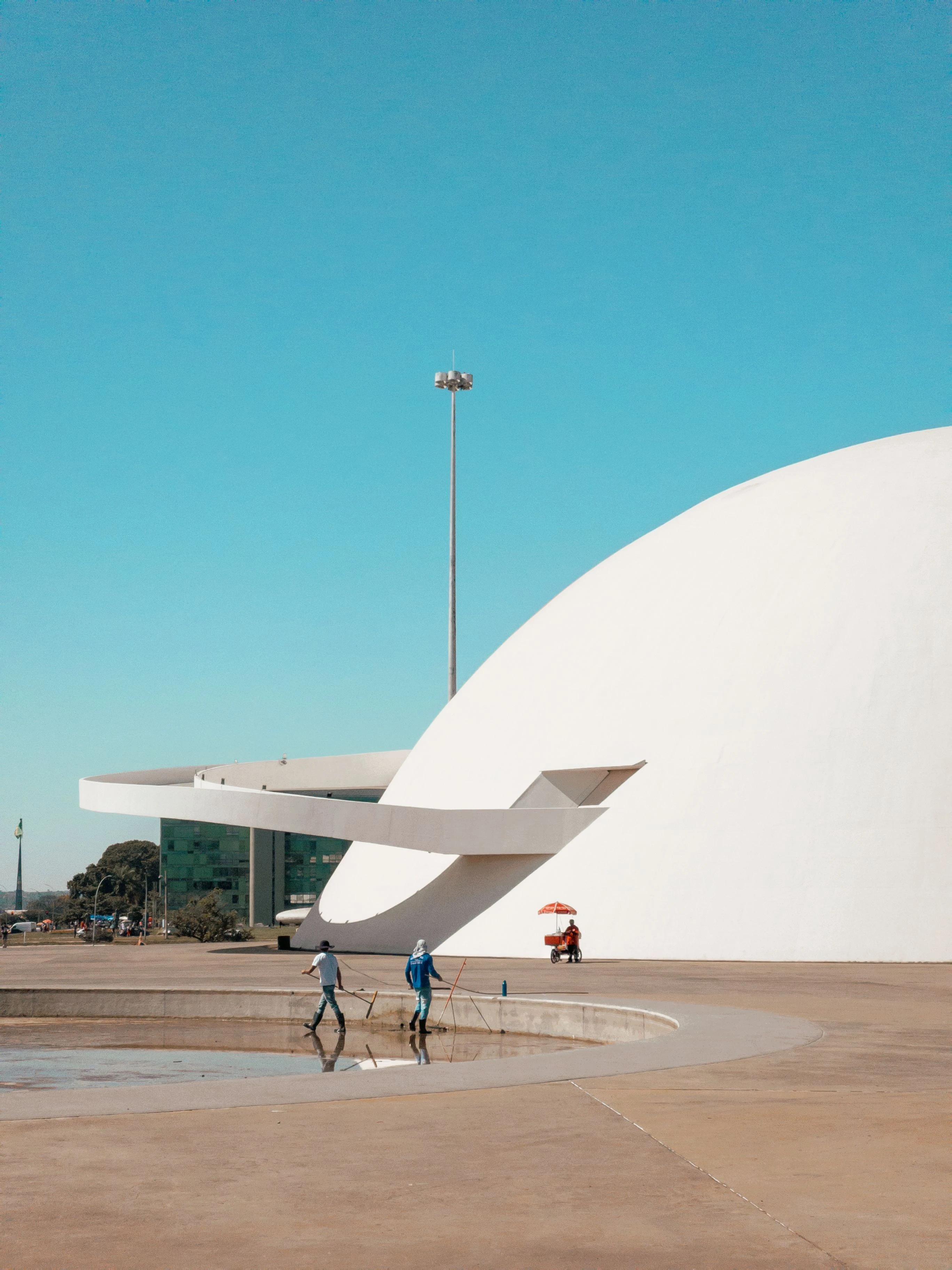 People walking beside the white curved form of Brasília’s Museu Nacional