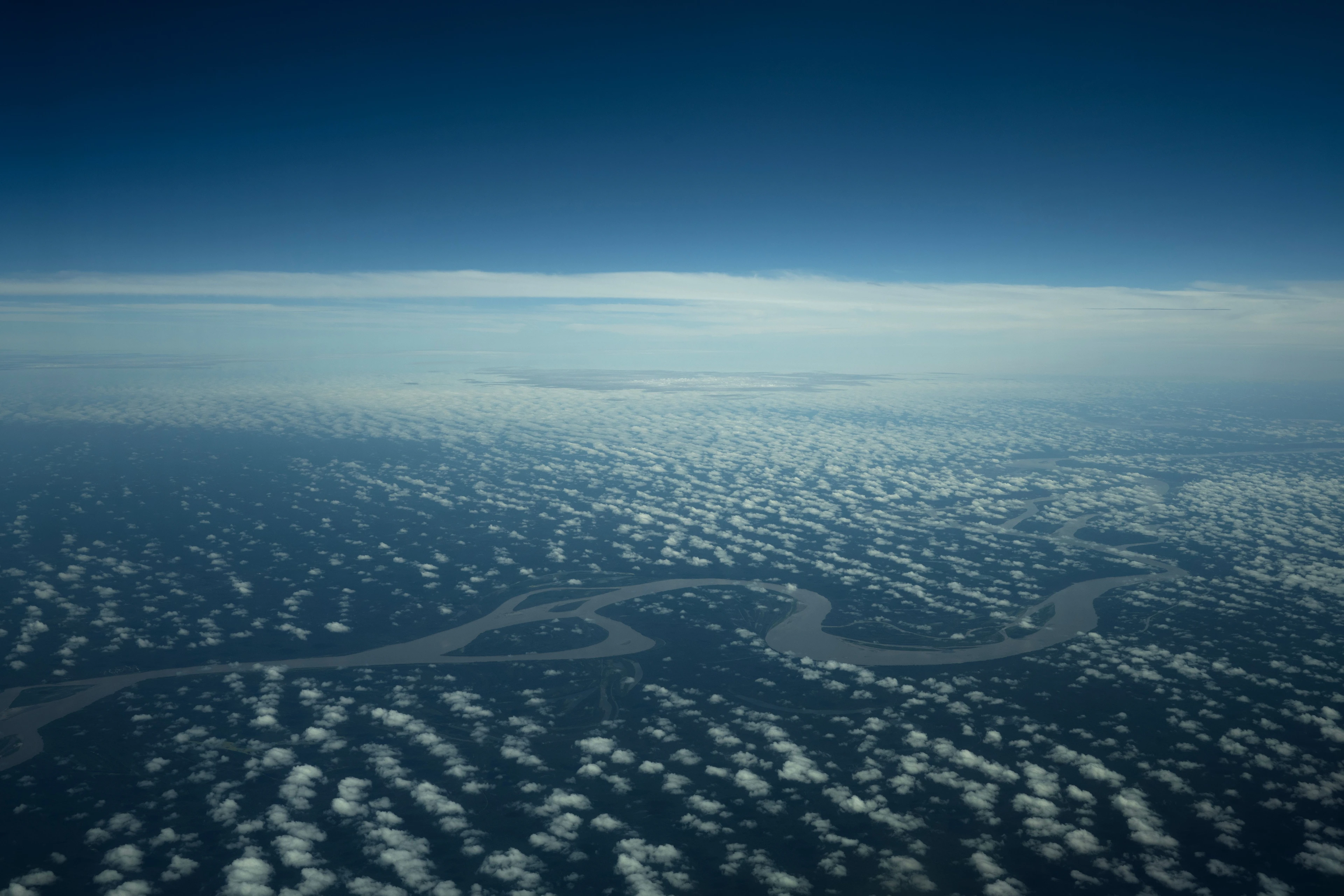 Amazon waterways seen from an aircraft beneath a field of clouds