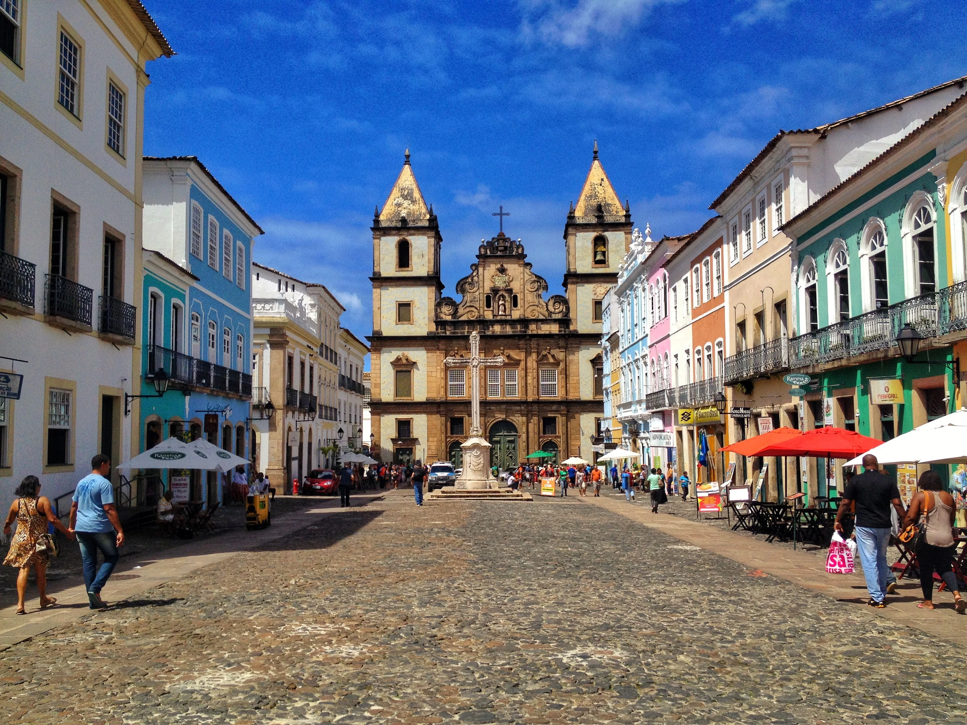 People and café umbrellas in Salvador’s colorful historic center beneath a blue sky