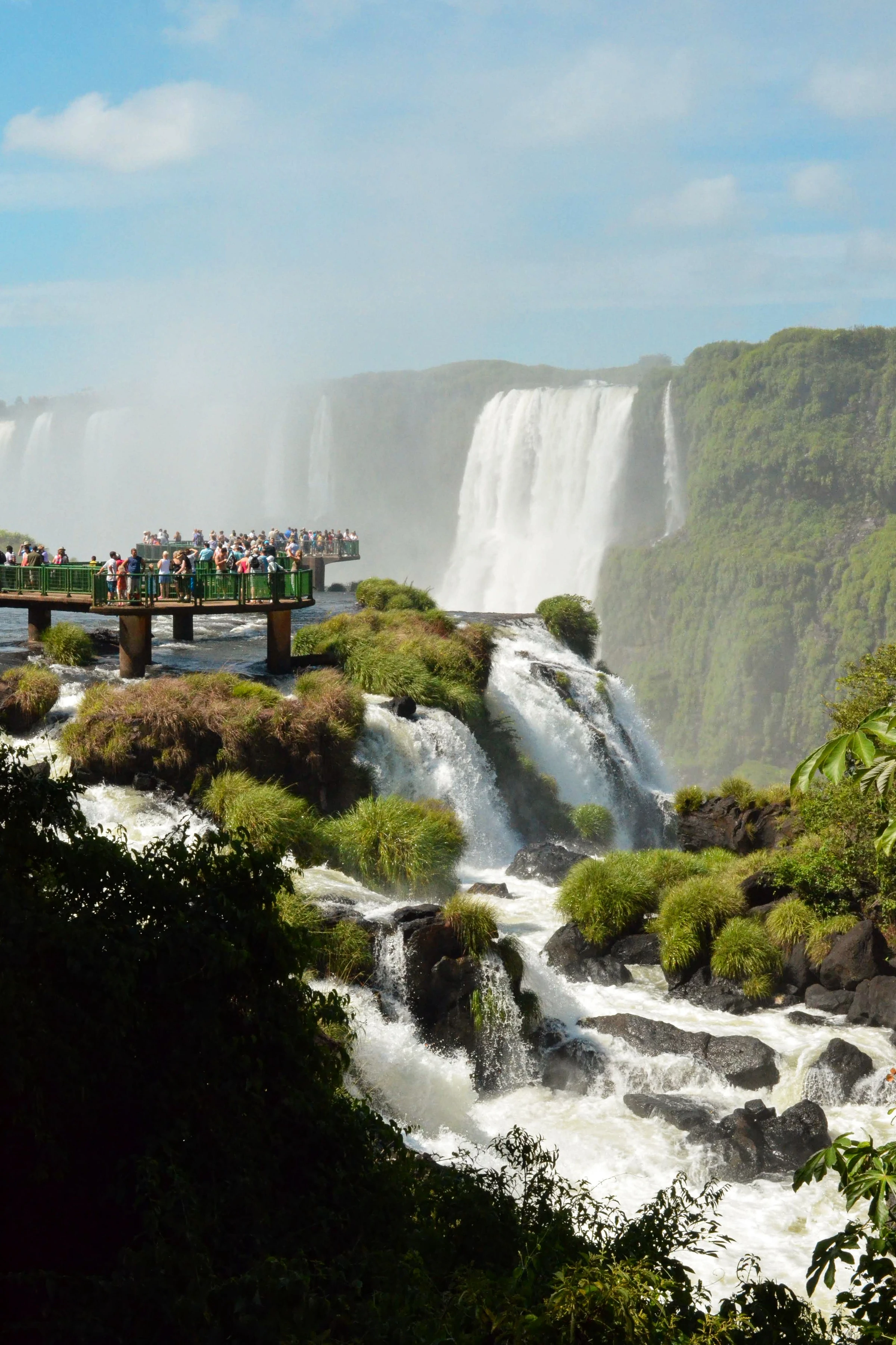 Visitors face the force of Iguaçu’s waterfalls beneath a vivid blue sky.