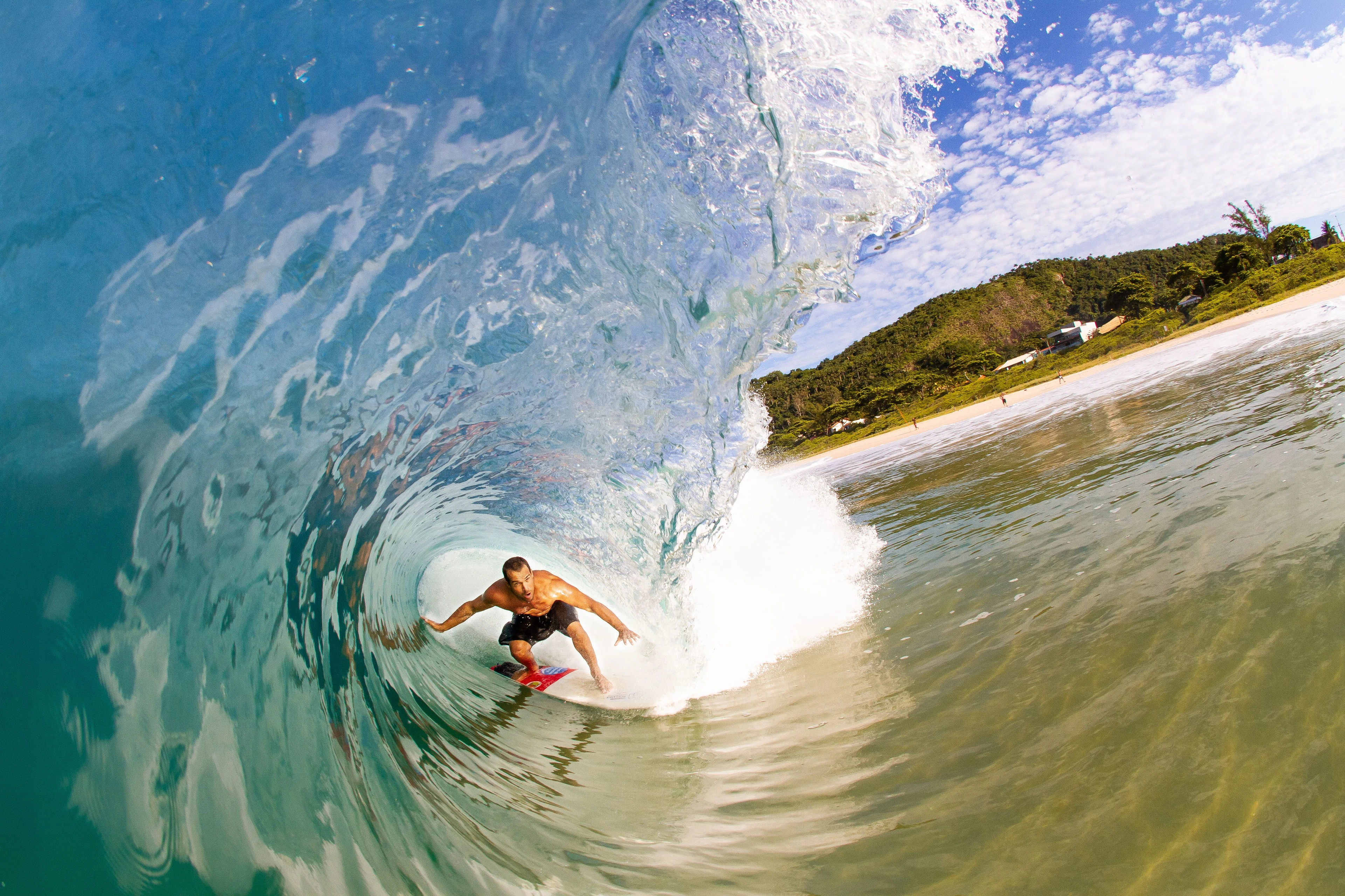A surfer riding inside a curling blue wave photographed from water level