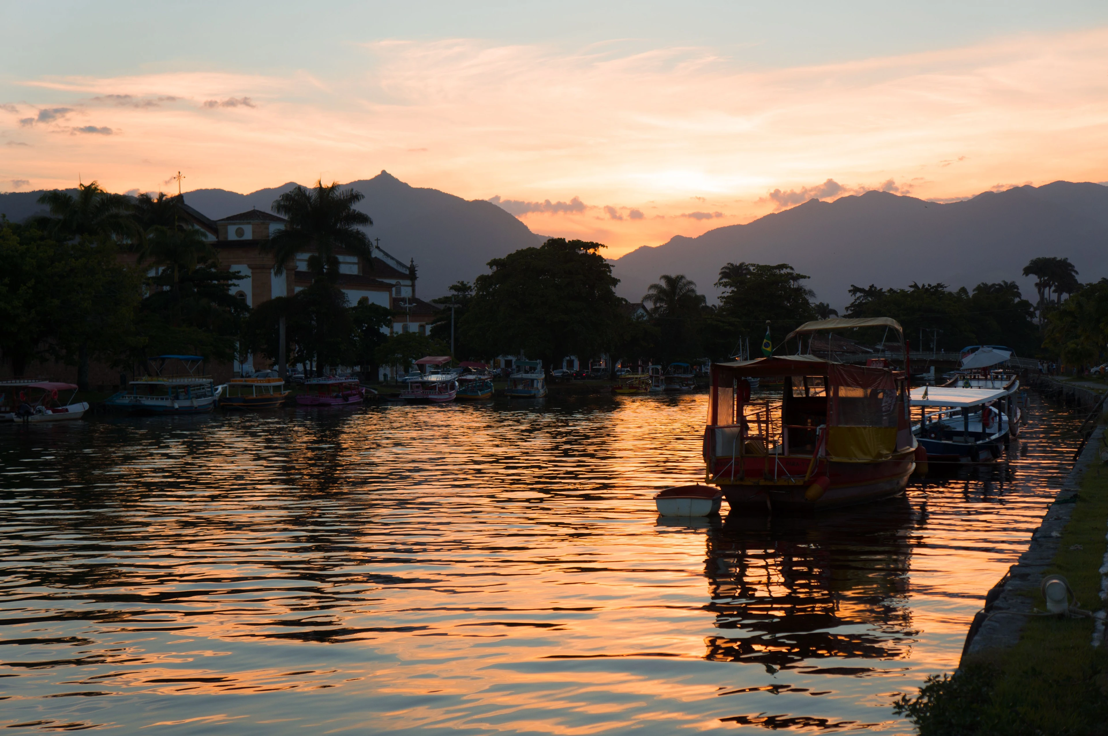 Wooden boats and orange evening light reflected in Paraty’s waterfront