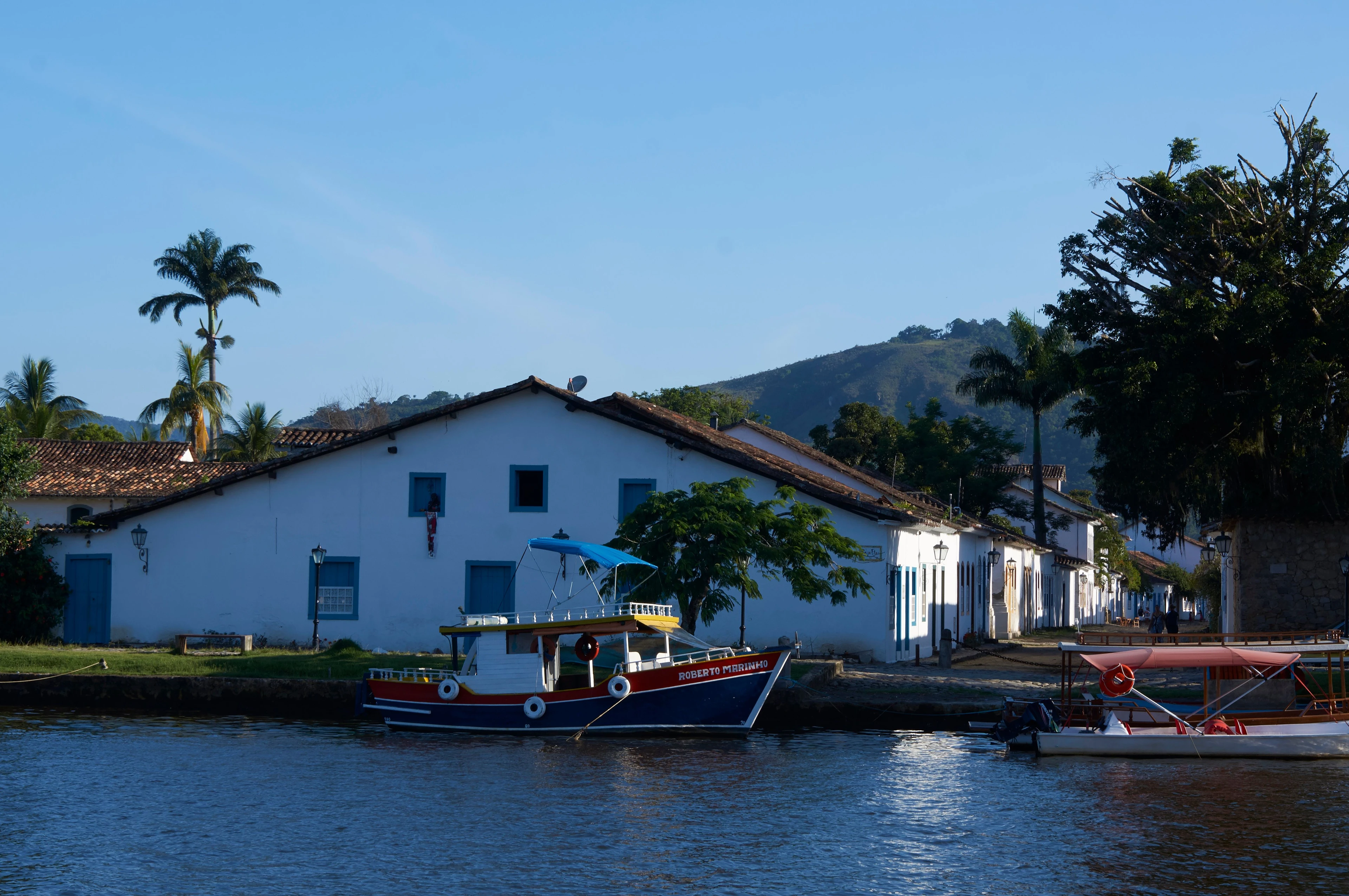 Colorful boats beside blue-and-white historic buildings at Paraty's waterfront