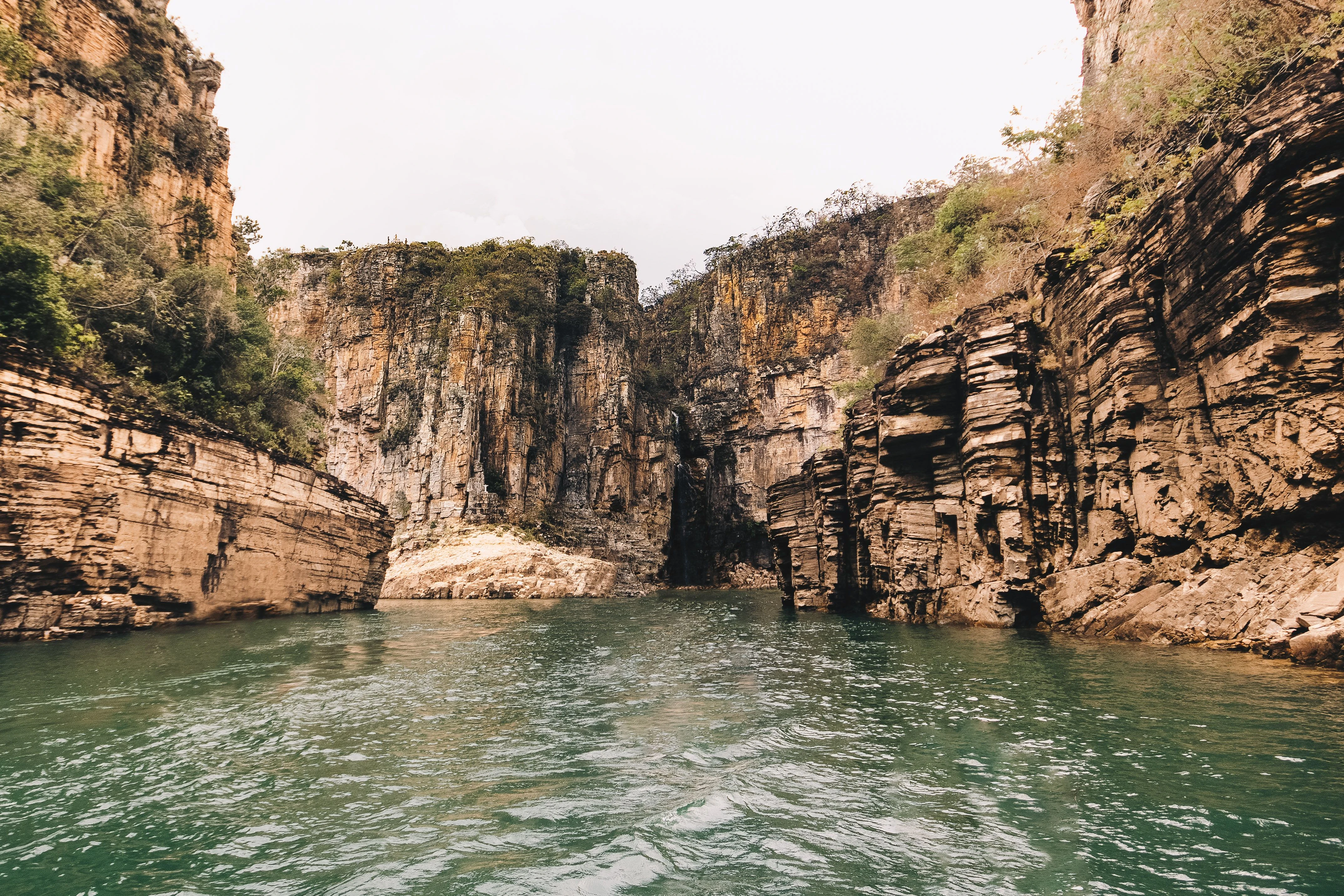 Tall, layered canyon walls rise directly from the water at Capitólio, Minas Gerais, shown as Brazilian canyon context.