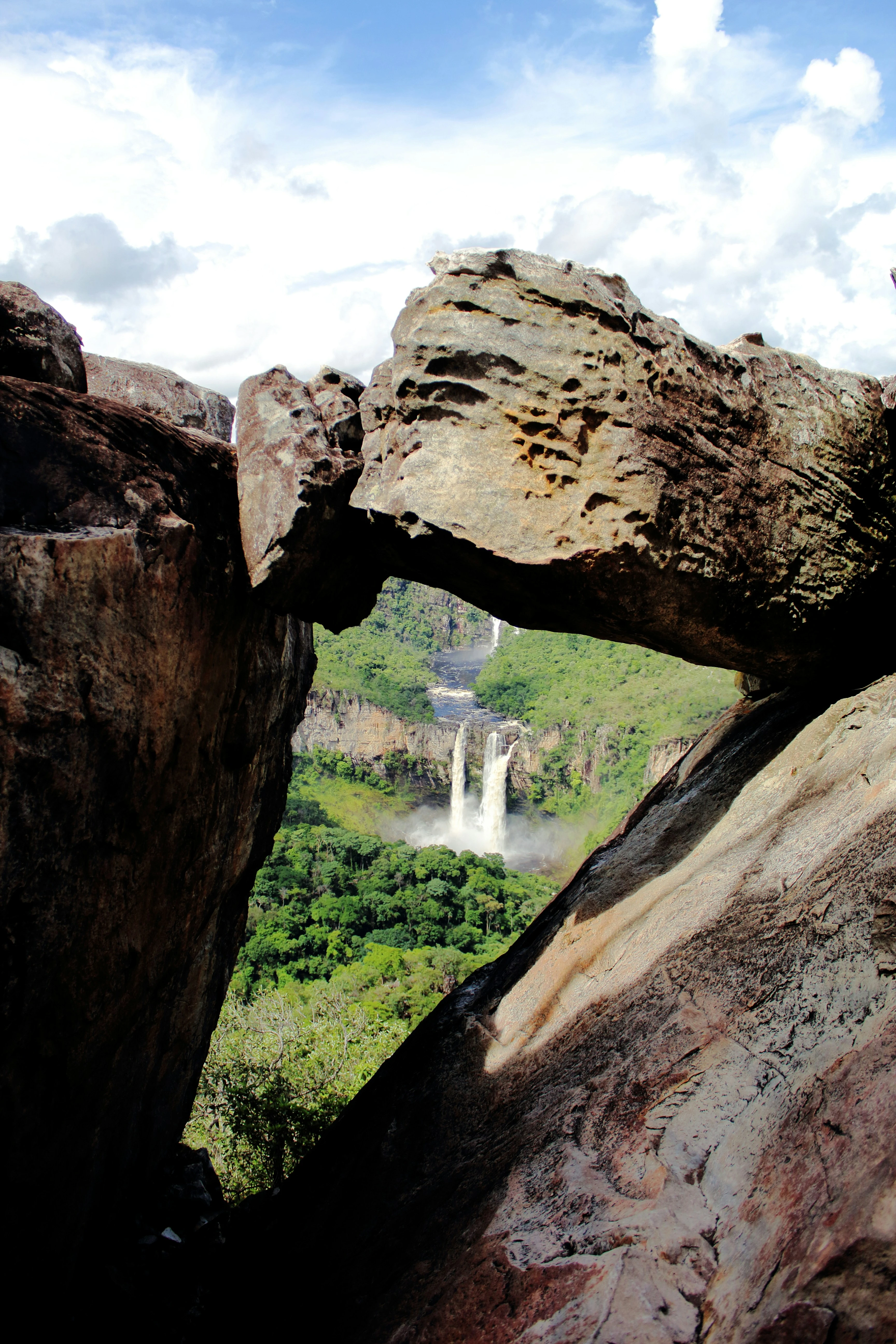 A natural rock window at Mirante da Janela frames distant Rio Preto waterfalls.