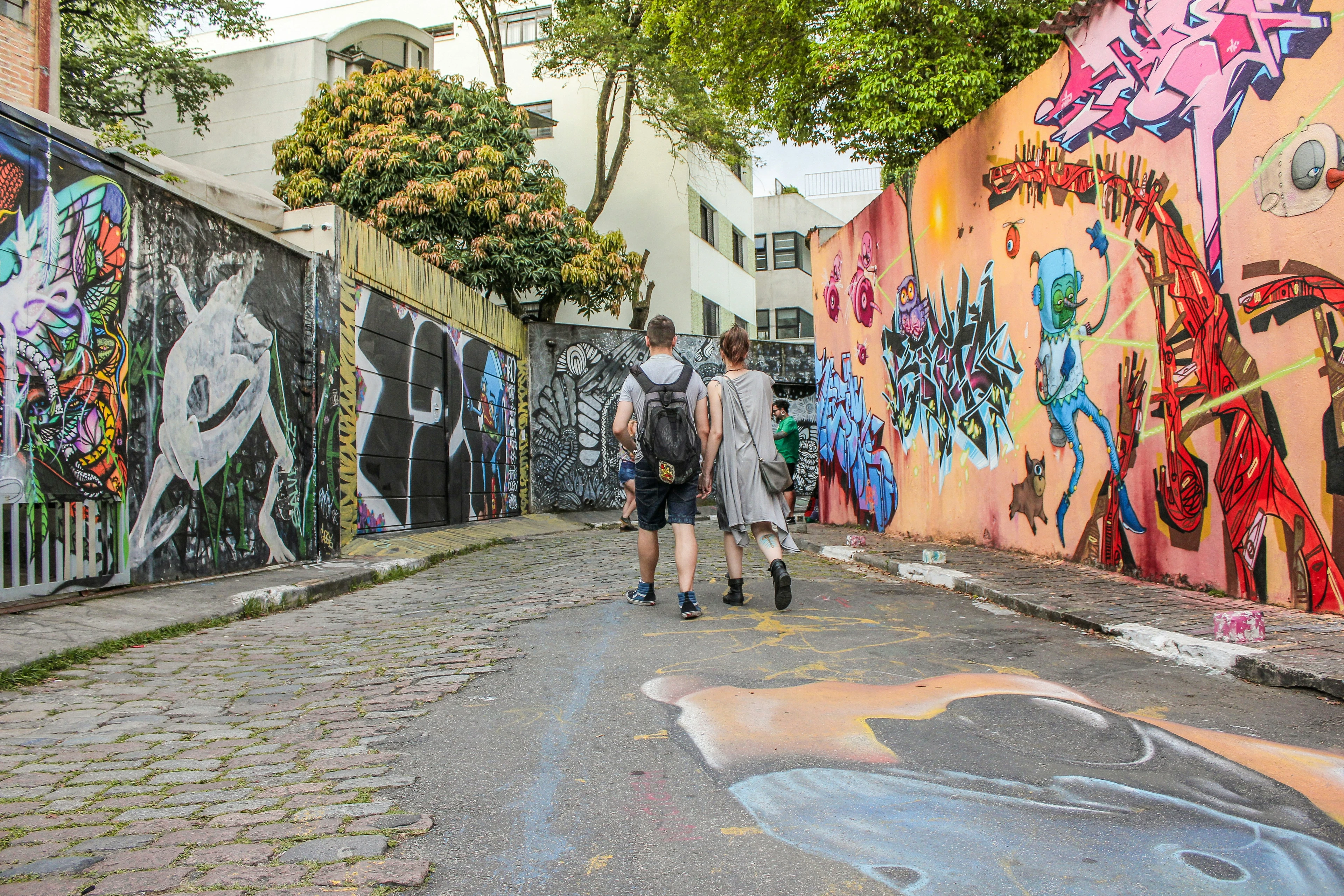 People walking between brightly painted walls in Beco do Batman