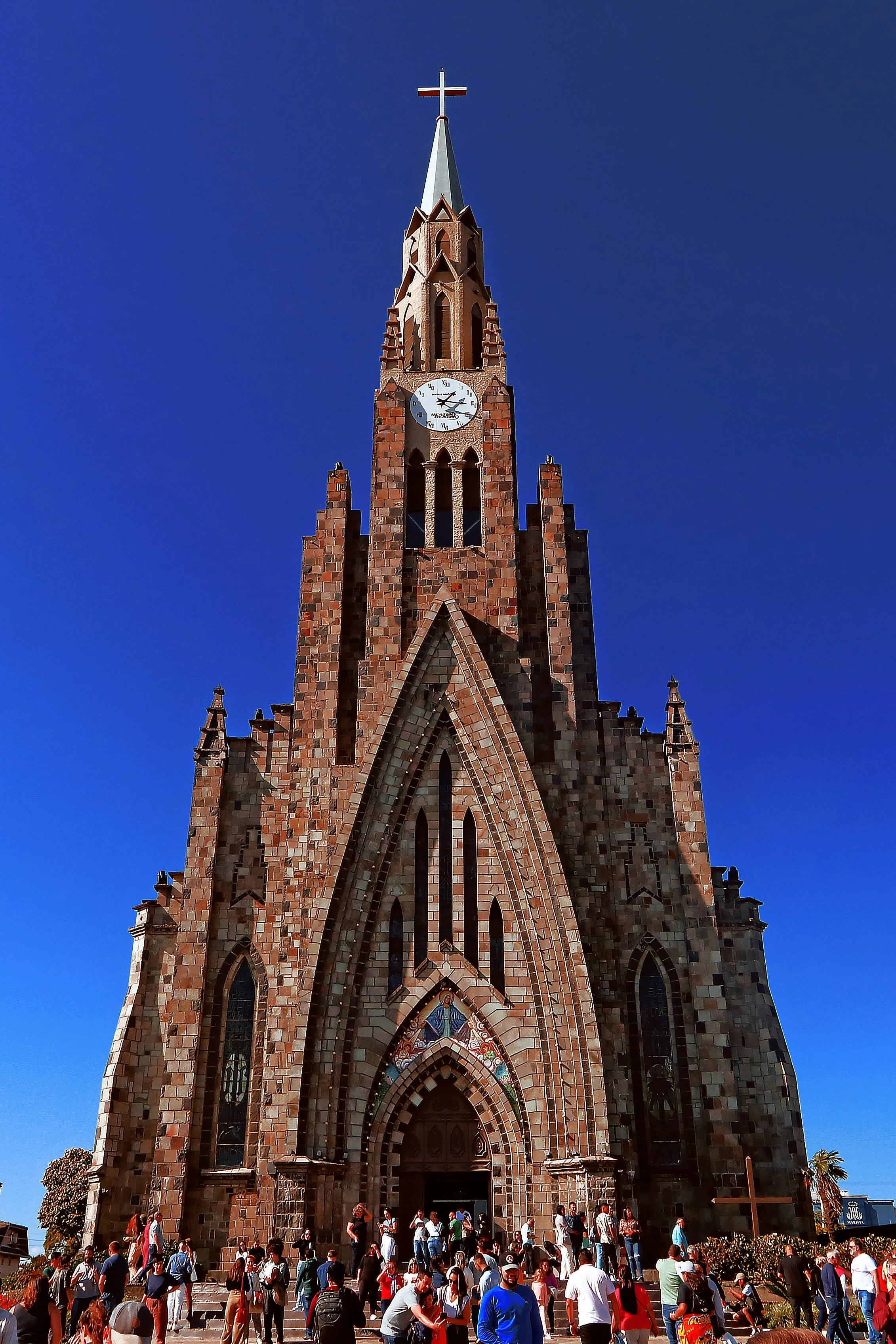 Canela’s stone cathedral rises above its square under blue sky.