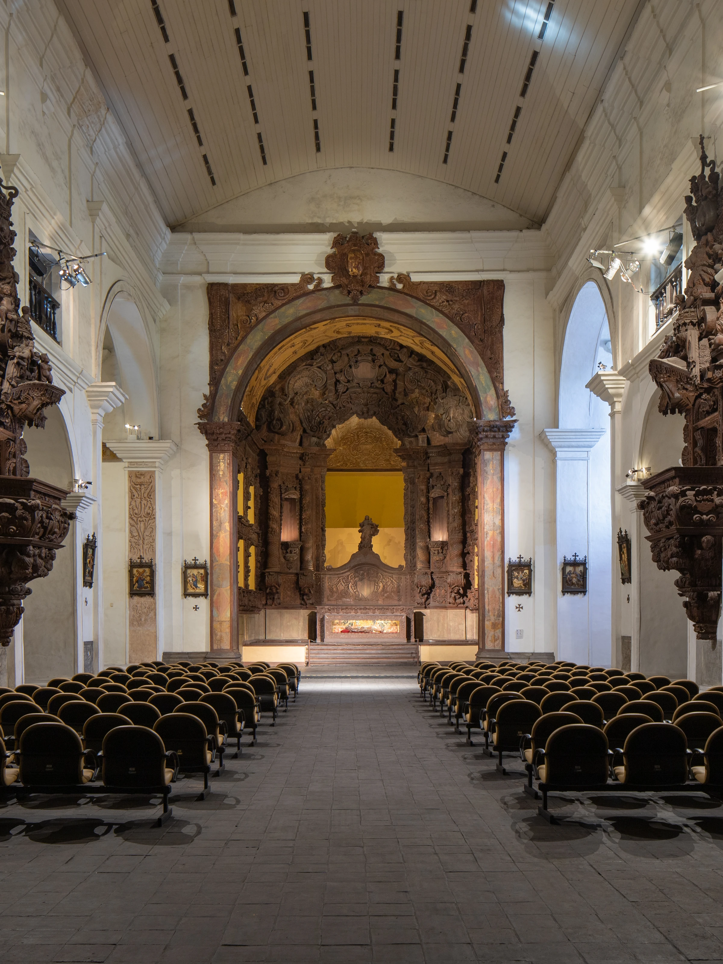 Carved wooden pulpits, rows of chairs and an illuminated altar inside Igreja de Santo Alexandre in Belém.